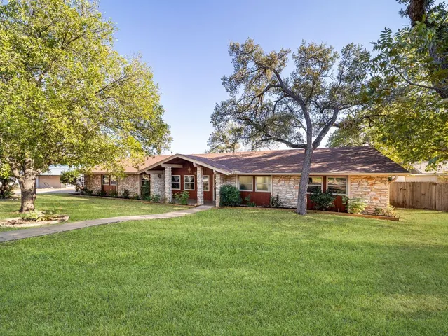 a view of a house next to a big yard with large trees