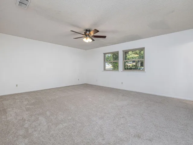 an empty room with windows and ceiling fan