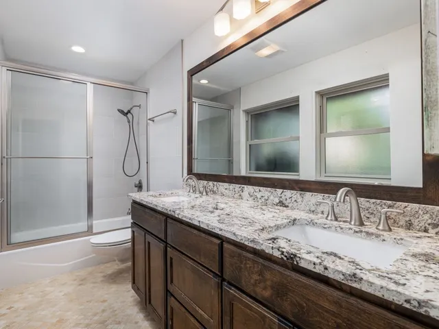 a bathroom with a granite countertop sink mirror and a shower