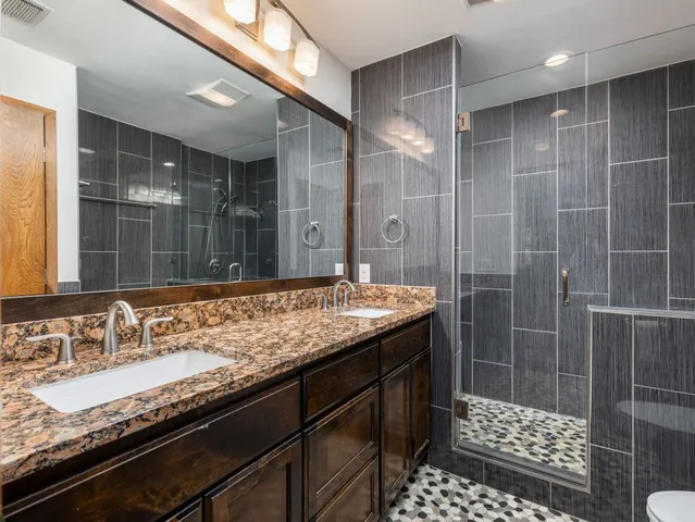 a bathroom with a granite countertop sink a vanity and a shower