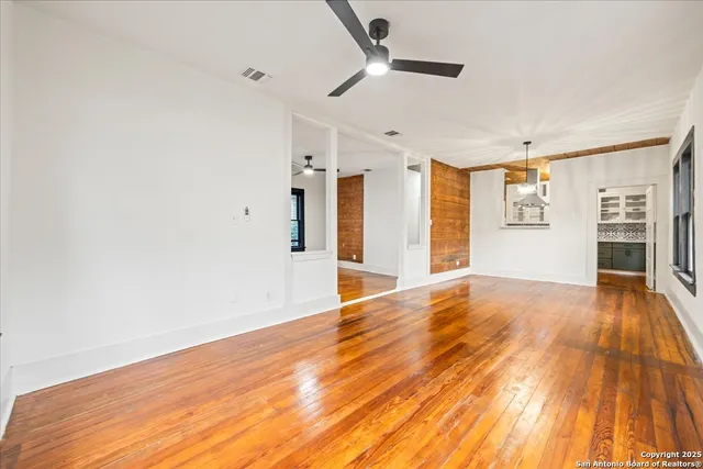 a view of empty room with wooden floor and fan