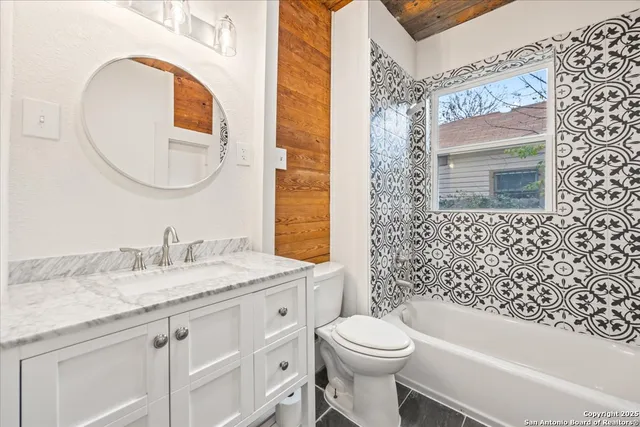 a bathroom with a granite countertop toilet sink and mirror