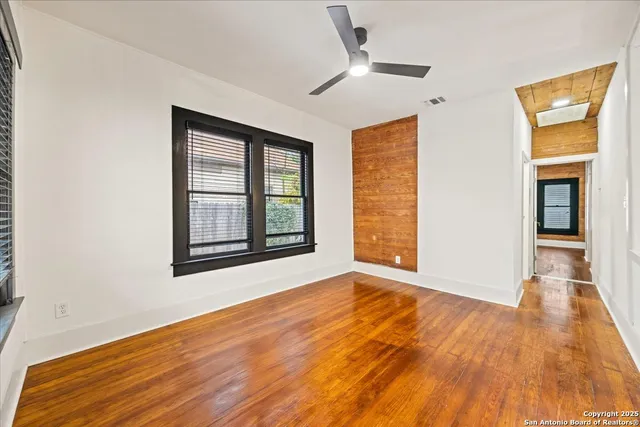 a view of an empty room with wooden floor and a window