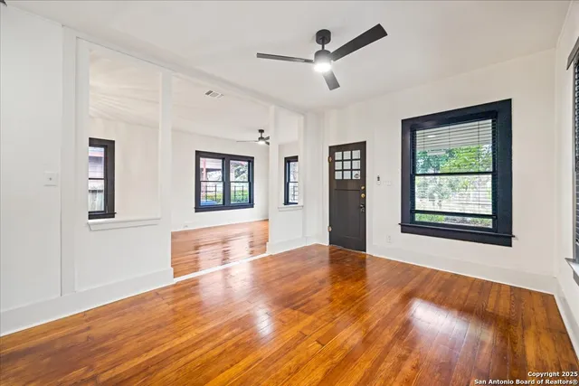 a view of an empty room with window and wooden floor