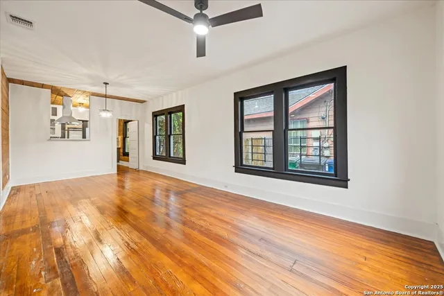 a view of an empty room with wooden floor and a window