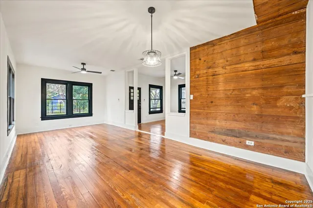 a view of an empty room with window and wooden floor