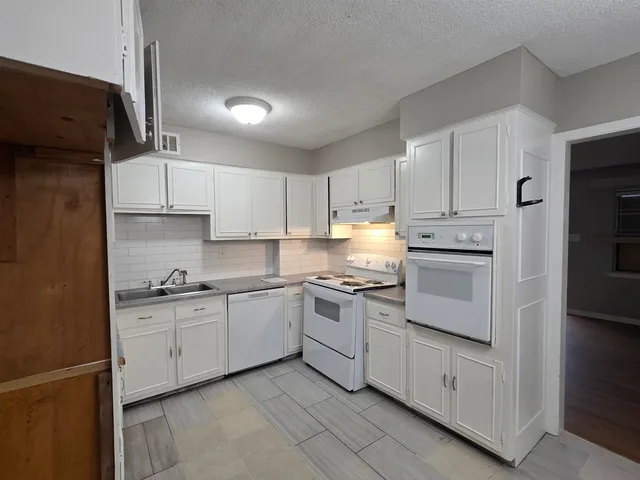 a kitchen with granite countertop white cabinets and white appliances