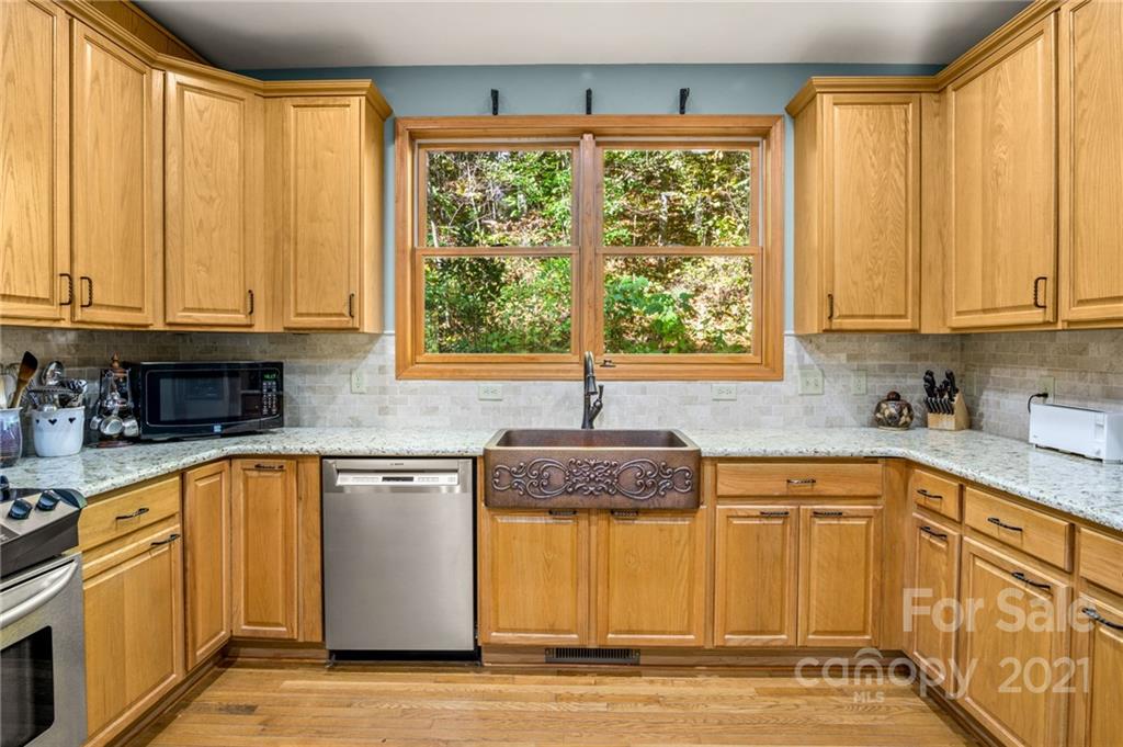 74 Apgar Road Candler, NC 28715 - Photo 9 of 46 a kitchen with stainless steel appliances granite countertop a refrigerator a sink dishwasher and white cabinets with wooden floor