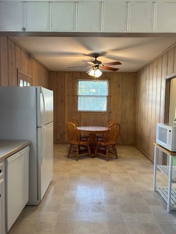 an empty room with chandelier fan and windows