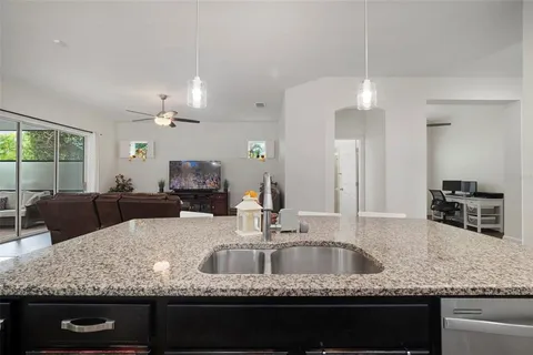 a living room with furniture kitchen area and a chandelier