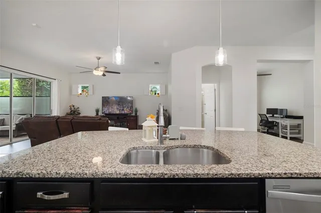 a living room with furniture kitchen area and a chandelier
