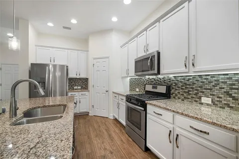a kitchen with granite countertop a sink a counter top stainless steel appliances and cabinets