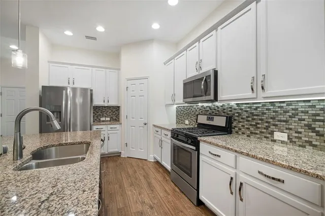 a kitchen with granite countertop a sink a counter top stainless steel appliances and cabinets