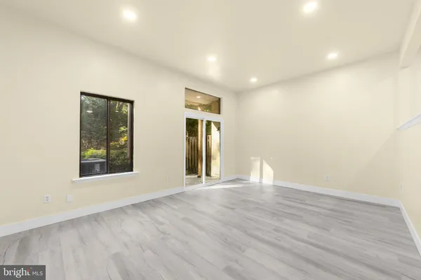 a view of an empty room with glass door and wooden floor