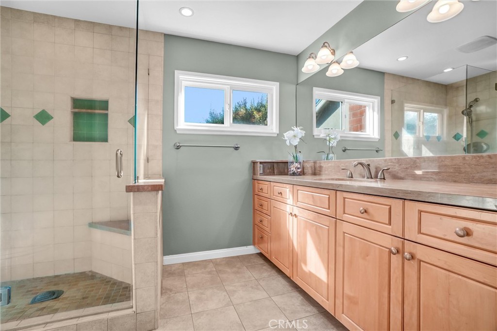 5552 Ridgebury Drive Huntington Beach, CA 92649 - Photo 17 of 31 a bathroom with a granite countertop sink a mirror and a shower
