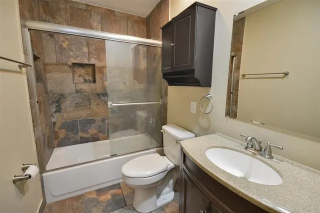 a bathroom with a granite countertop sink toilet and shower