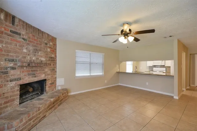 a view of kitchen and empty room with fireplace