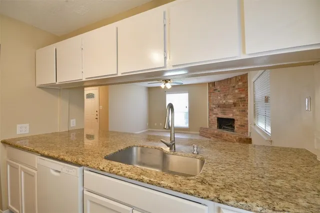 a kitchen with granite countertop a sink and white cabinets