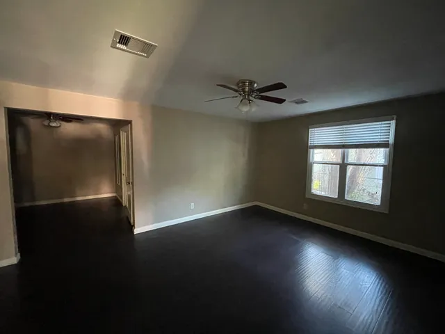 a view of an empty room with a window and wooden floor