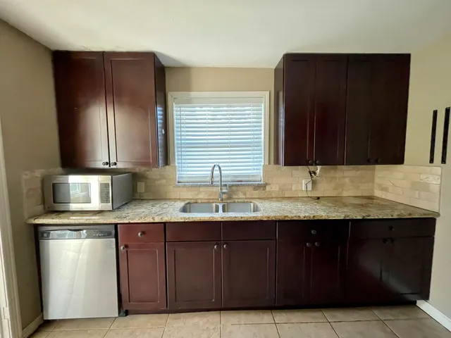 a kitchen with granite countertop stainless steel appliances a sink stove and cabinets