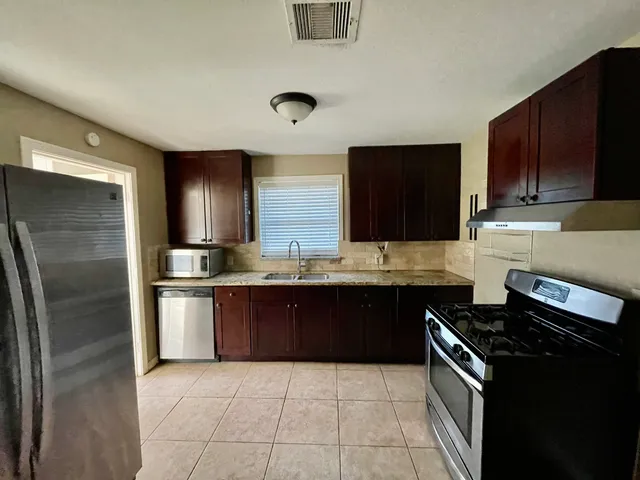 a kitchen with stainless steel appliances granite countertop a stove a refrigerator and a sink