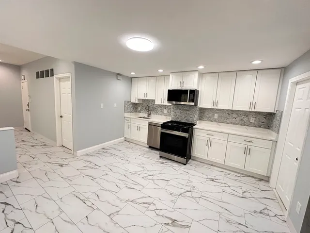 a kitchen with stainless steel appliances a sink a stove a microwave a refrigerator and cabinets