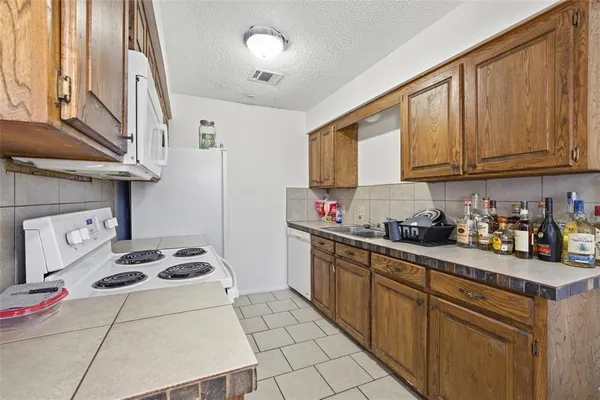 a kitchen with granite countertop a stove a sink dishwasher and cabinets with wooden floor