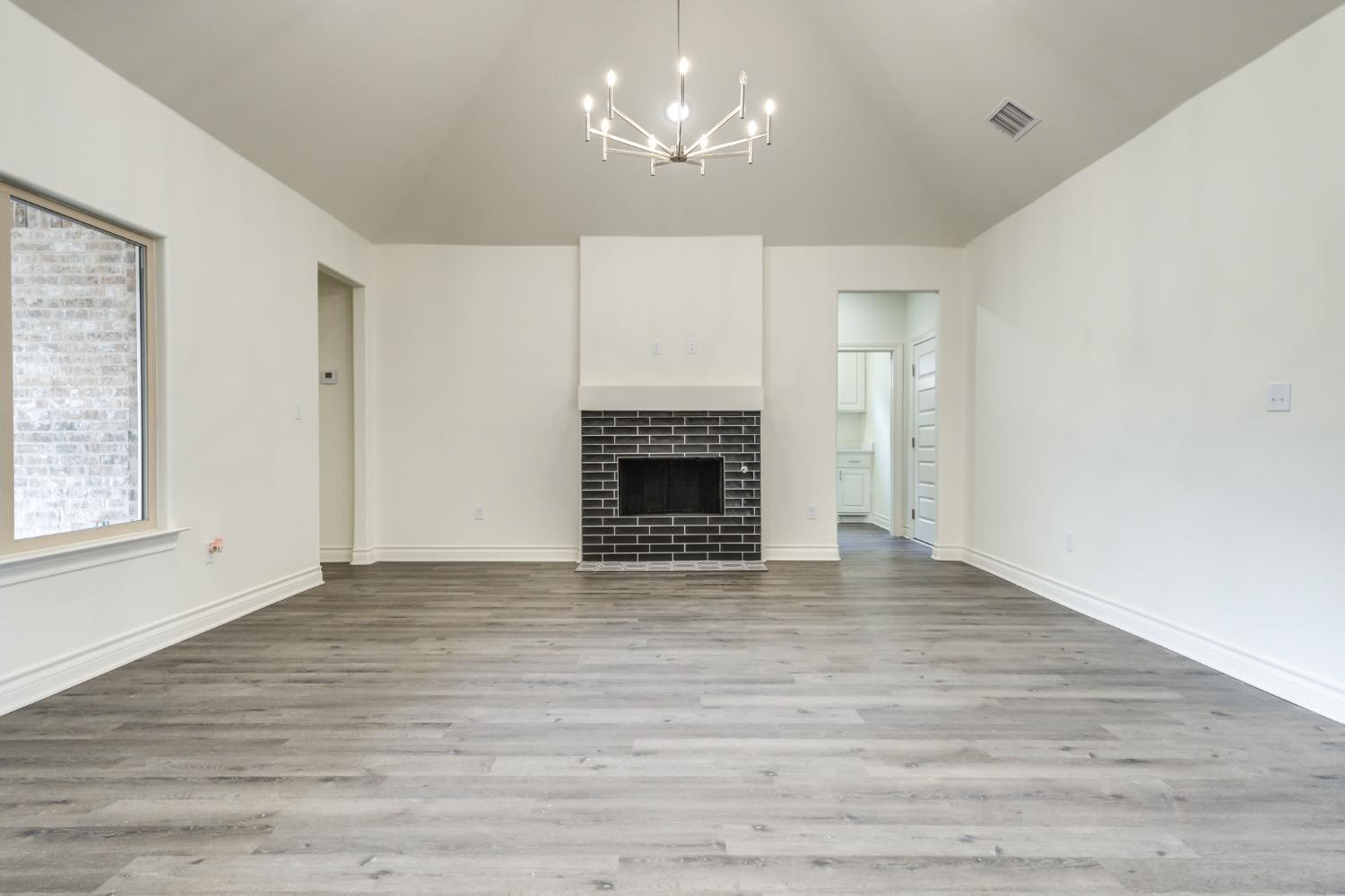 3712 144th Street Lubbock, TX 79423 - Photo 23 of 46 a view of a livingroom with a fireplace a chandelier and windows