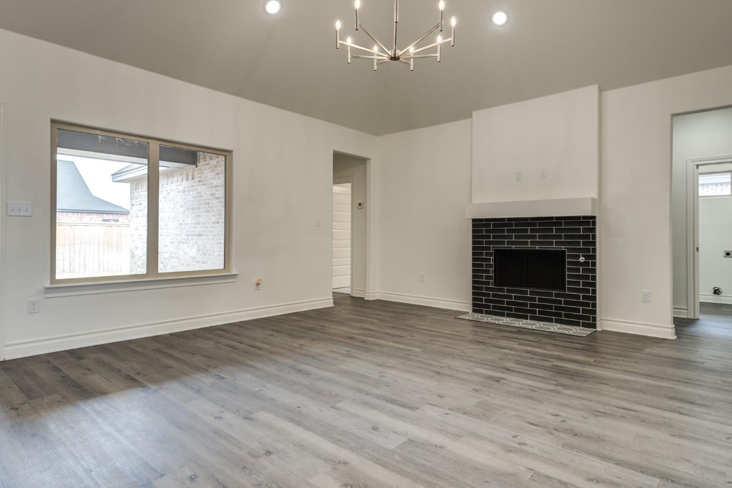 3712 144th Street Lubbock, TX 79423 - Photo 24 of 46 an empty room with wooden floor fireplace and windows