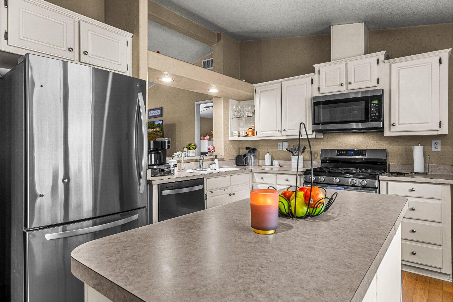9425 Mosquito Road Placerville, CA 95667 - Photo 54 of 74 a kitchen with stainless steel appliances granite countertop a refrigerator a stove top oven a sink dishwasher and white cabinets with wooden floor