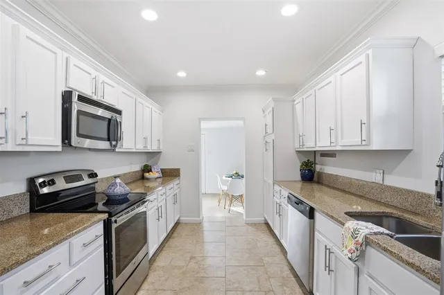 a kitchen with granite countertop white cabinets and stainless steel appliances