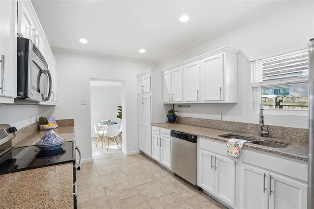 a kitchen with a sink dishwasher stove and white cabinets