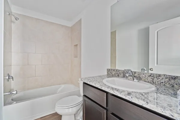 a bathroom with a granite countertop sink a toilet and bathtub
