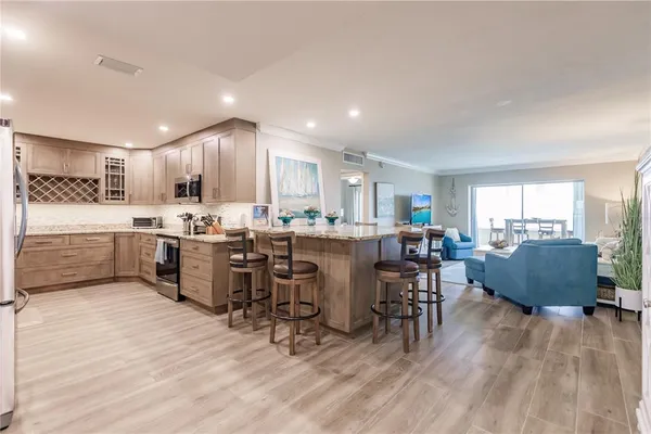 a living room with stainless steel appliances kitchen island granite countertop furniture and a wooden floors