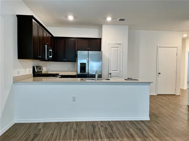 a view of kitchen with stainless steel appliances wooden cabinets and entryway