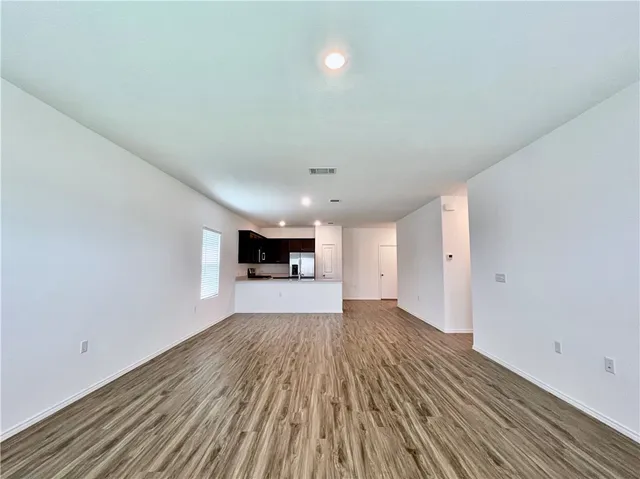 a view of a big room with wooden floor and windows