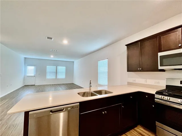 a kitchen with a sink and a stove top oven with wooden floor