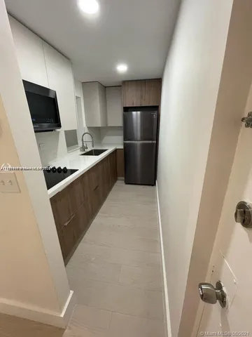 a kitchen with white cabinets and refrigerator