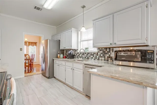 a kitchen with stainless steel appliances granite countertop a stove a sink and white cabinets