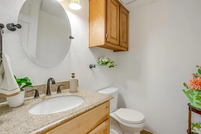 a bathroom with a granite countertop toilet sink and mirror