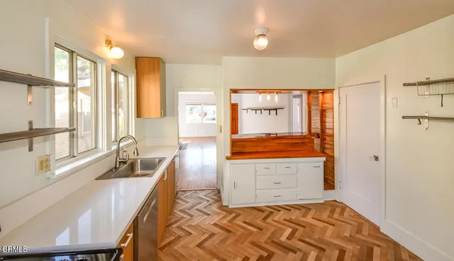 a view of a kitchen with a sink and dishwasher with wooden floor