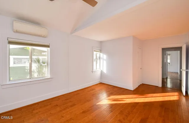 a view of empty room with wooden floor and fan