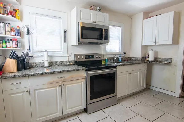 a kitchen with granite countertop white cabinets and white appliances
