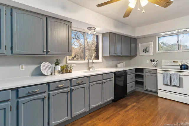 a kitchen with granite countertop a sink cabinets stainless steel appliances and a window