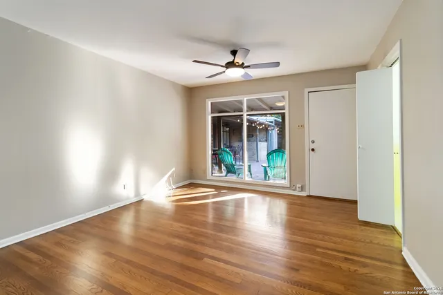 a view of an empty room with wooden floor and a window