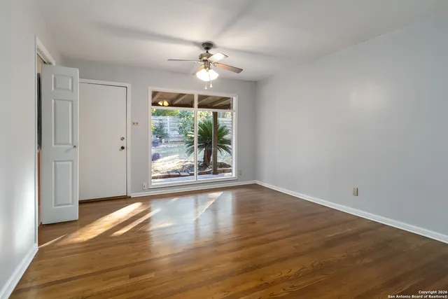 a view of an empty room with wooden floor and a window