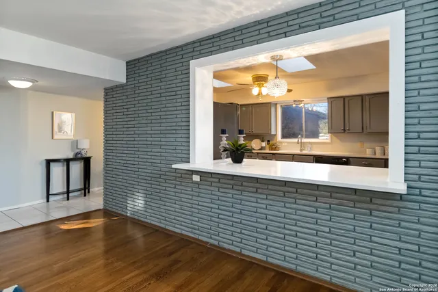a view of kitchen with kitchen island a sink a wooden floor and a large window