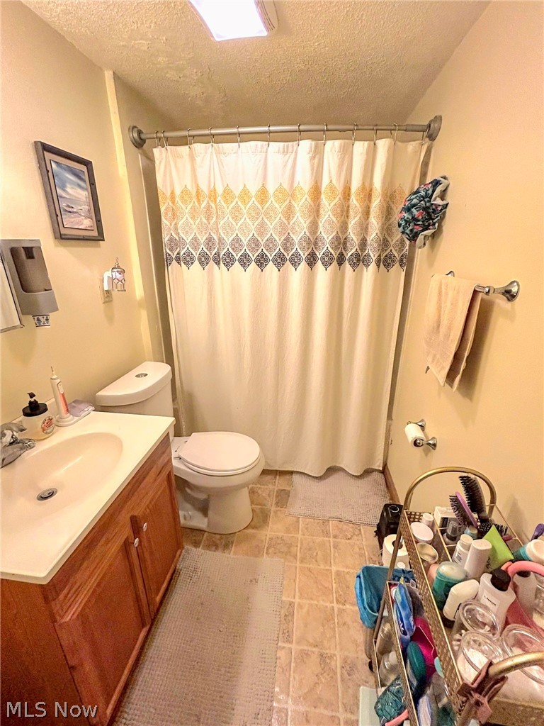 4726 Warren - Sharon Road Vienna, OH 44473 - Photo 13 of 15 Bathroom with tile floors, vanity, toilet, and a textured ceiling