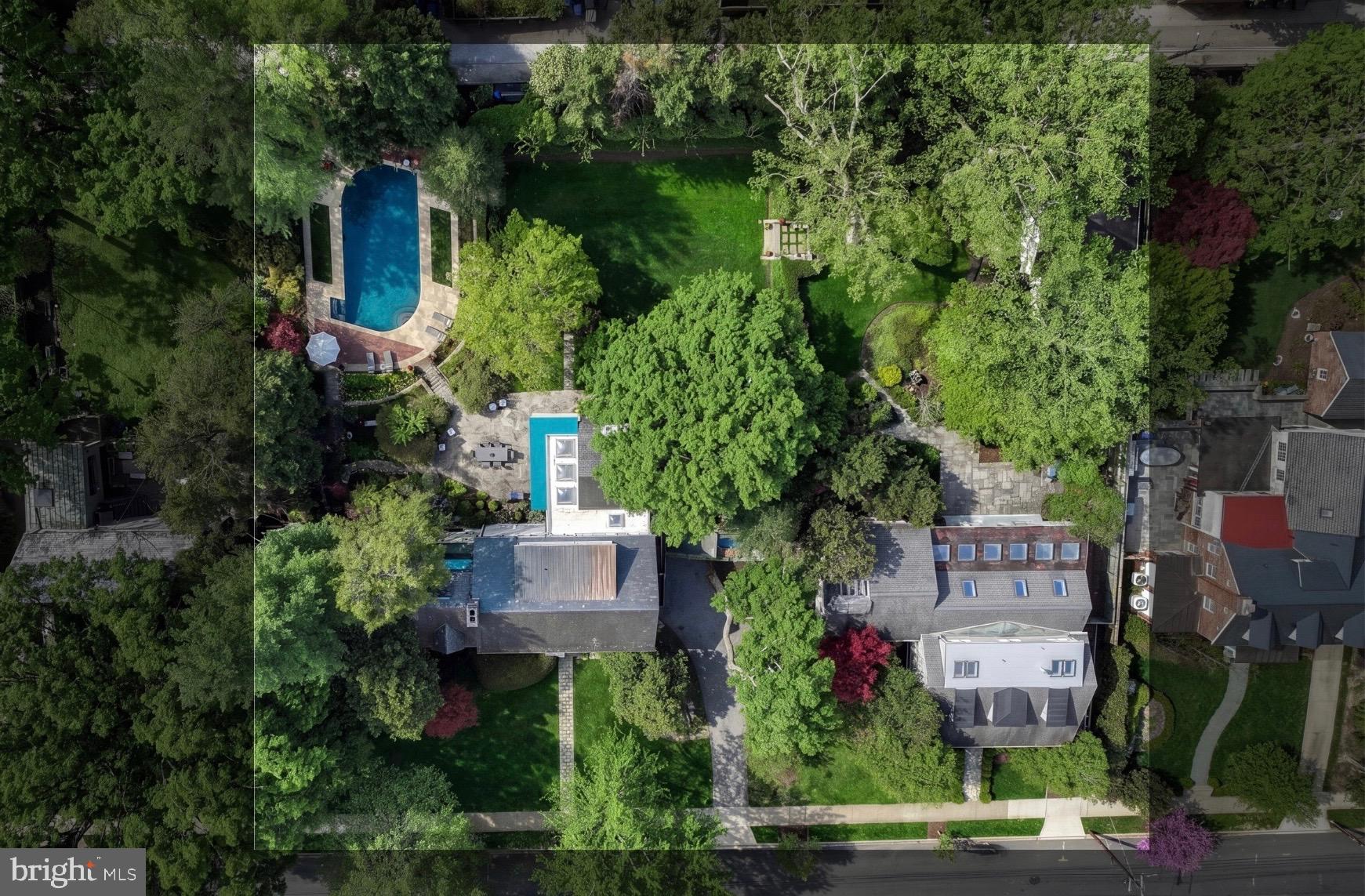 an aerial view of a house with outdoor space and trees all around