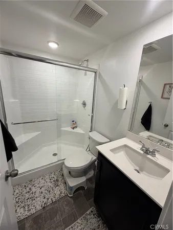 a bathroom with a sink a toilet a mirror and shower